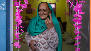 An elderly woman shows the indelible ink mark on her finger after casting vote